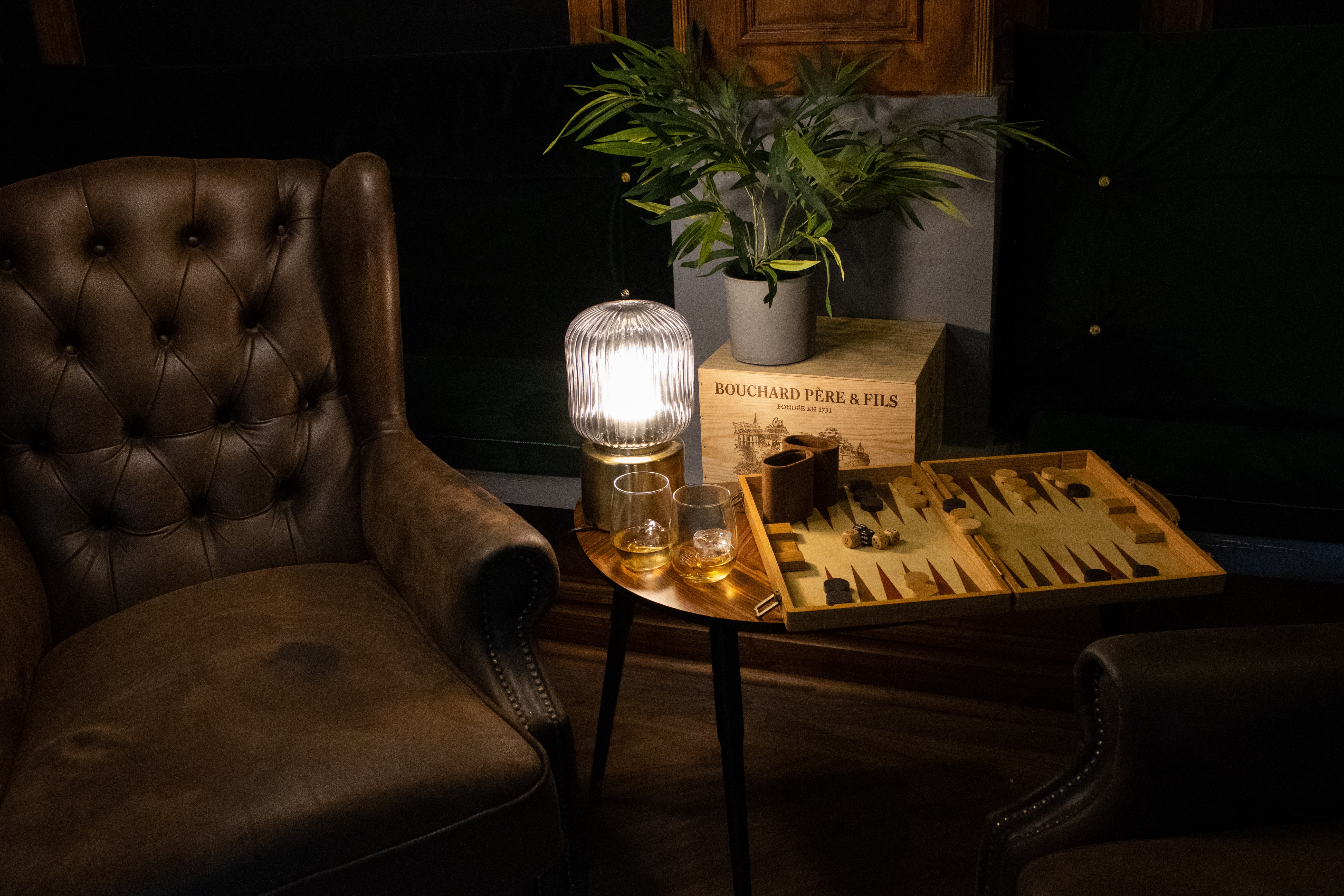 brown leather chair in dimly lit room with candle drink and game on a table